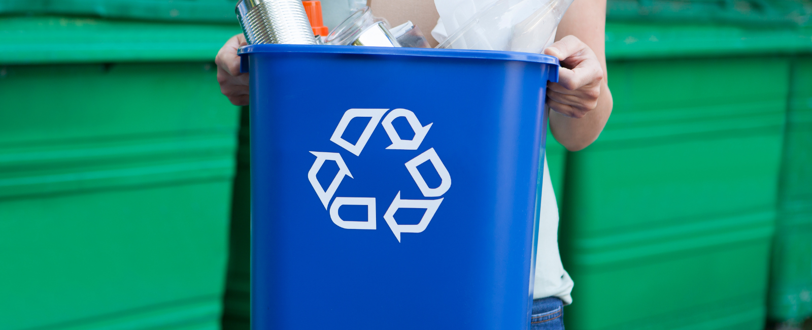 Person holding a blue recycling bin.